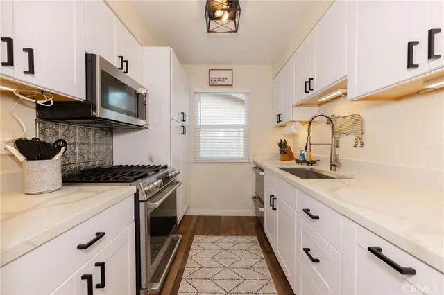 a kitchen with granite countertop a sink stainless steel appliances and cabinets