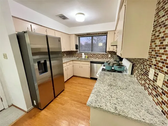 a kitchen with stainless steel appliances granite countertop a refrigerator and a stove