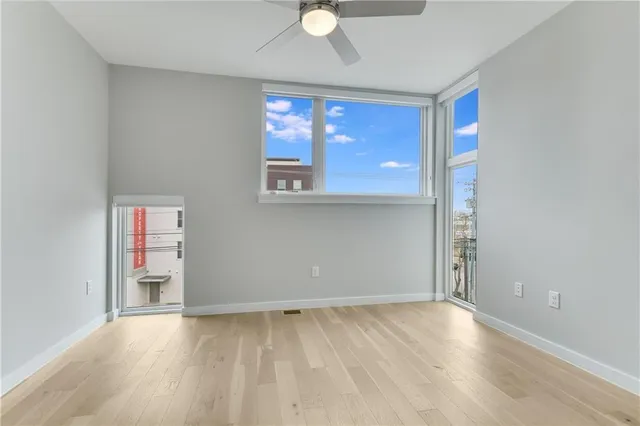 an empty room with wooden floor and windows