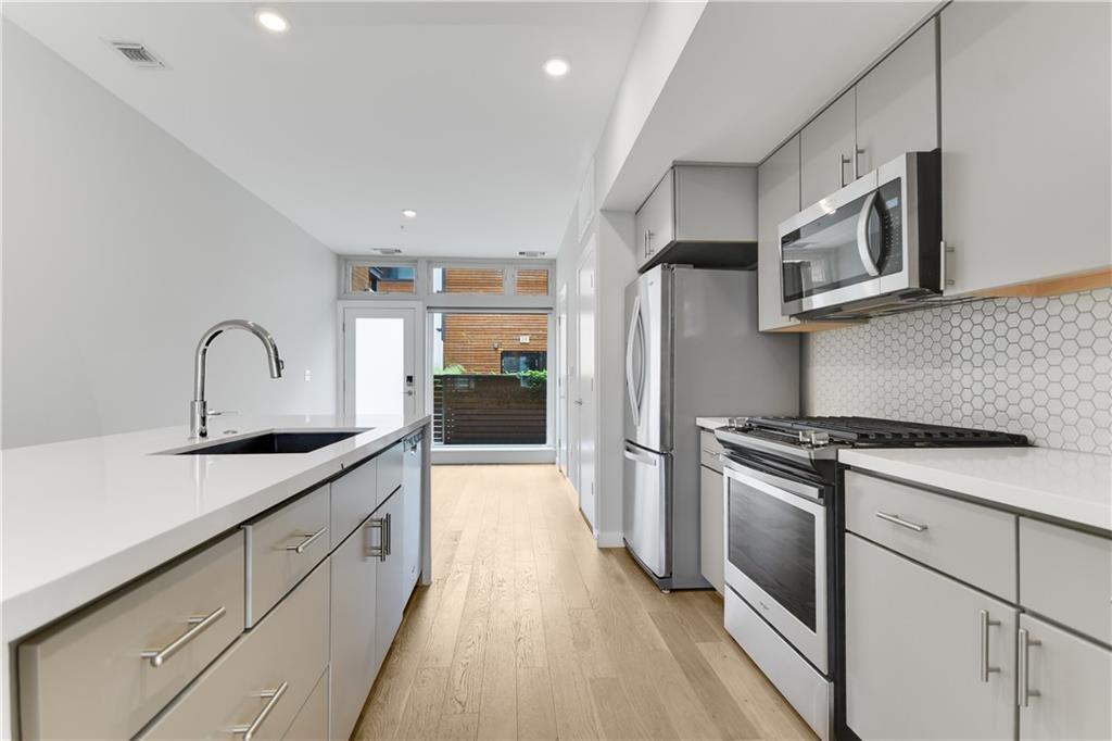 2002 East 7th Street, Unit 212 Austin, TX 78702 - Photo 3 of 23 a kitchen with stainless steel appliances granite countertop a sink stove and refrigerator