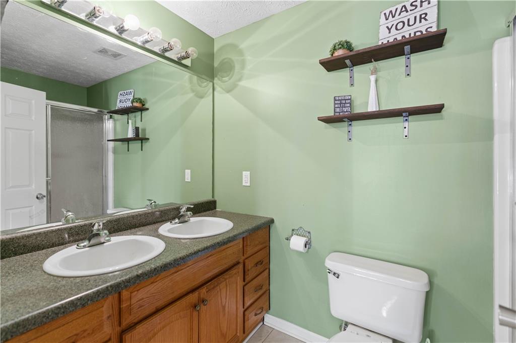 7540 County Line Road Lula, GA 30554 - Photo 14 of 62 a bathroom with a granite countertop sink a toilet and a mirror