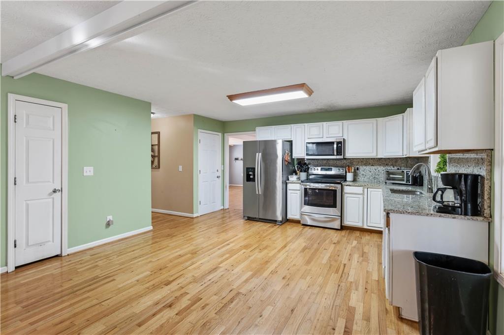 7540 County Line Road Lula, GA 30554 - Photo 19 of 62 a kitchen with stainless steel appliances granite countertop a refrigerator a stove top oven a sink and dishwasher with wooden floor