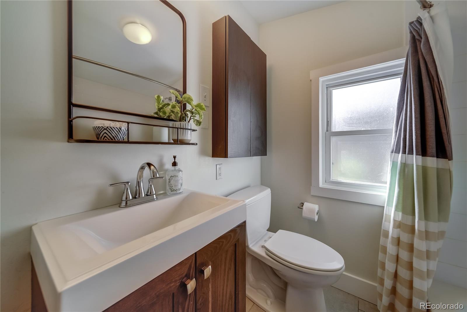 5129 Zuni Street Denver, CO 80221 - Photo 31 of 40 a bathroom with a sink toilet and mirror