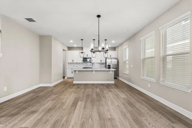a view of a kitchen with wooden floor and stainless steel appliances