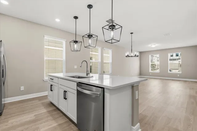 a kitchen with stainless steel appliances granite countertop a sink a window and wooden floor