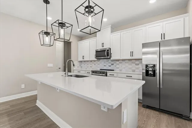 a kitchen with stainless steel appliances a sink a refrigerator a center island a stove and cabinets