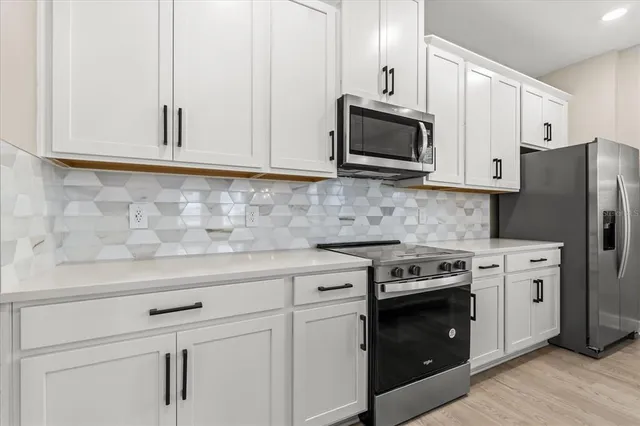 a kitchen with stainless steel appliances granite countertop white cabinets sink and stove