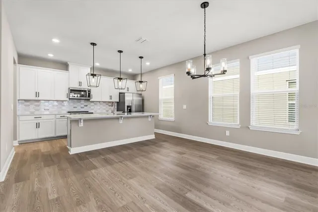 a large kitchen with granite countertop a stove a sink a center island and wooden floor