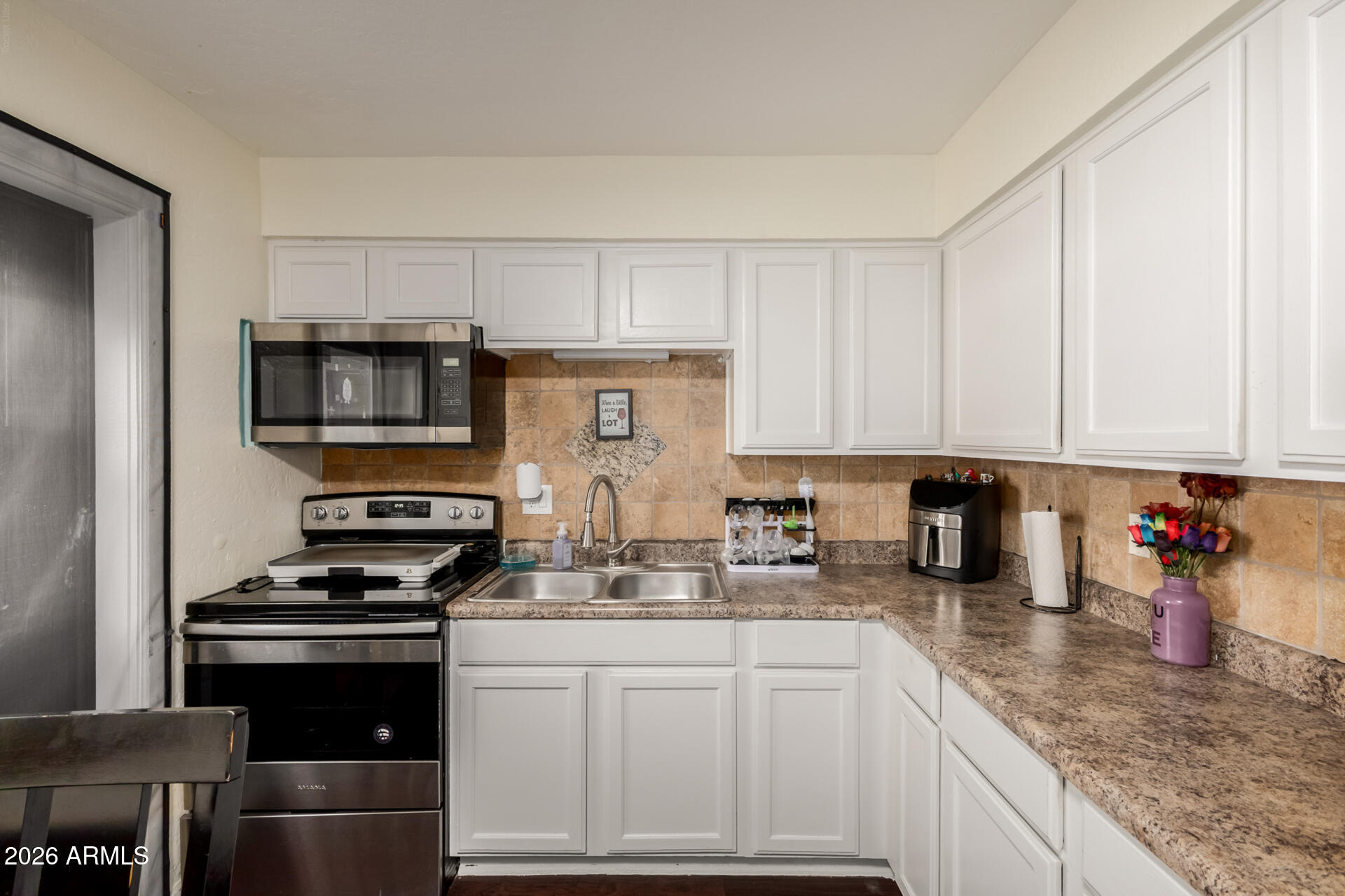 4615 North 39th Avenue, Unit 23 Phoenix, AZ 85019 - Photo 3 of 15 a kitchen with stainless steel appliances granite countertop a stove a sink dishwasher and a microwave oven with white cabinets