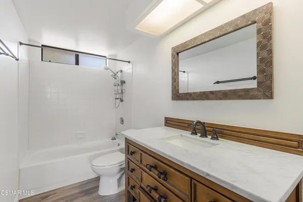 a bathroom with a granite countertop sink a toilet and bathtub