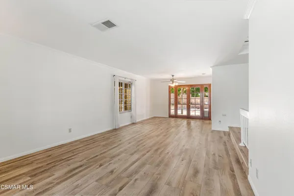 a view of an empty room with wooden floor and window