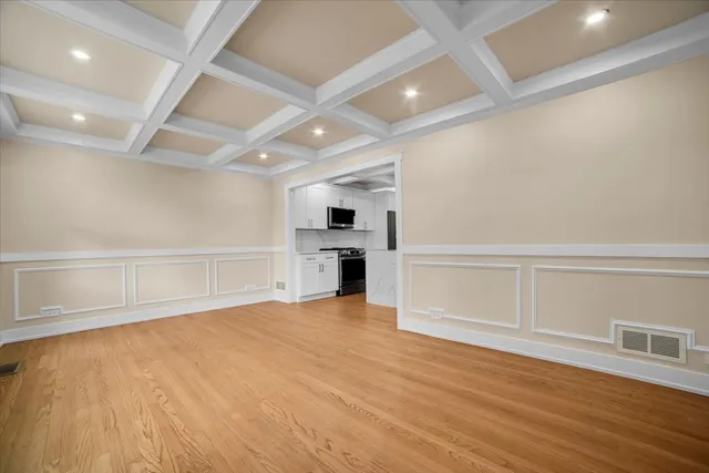 an empty room with wooden floor fireplace and windows