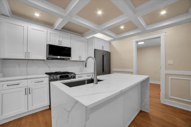 a kitchen that has a sink a stove and white cabinets