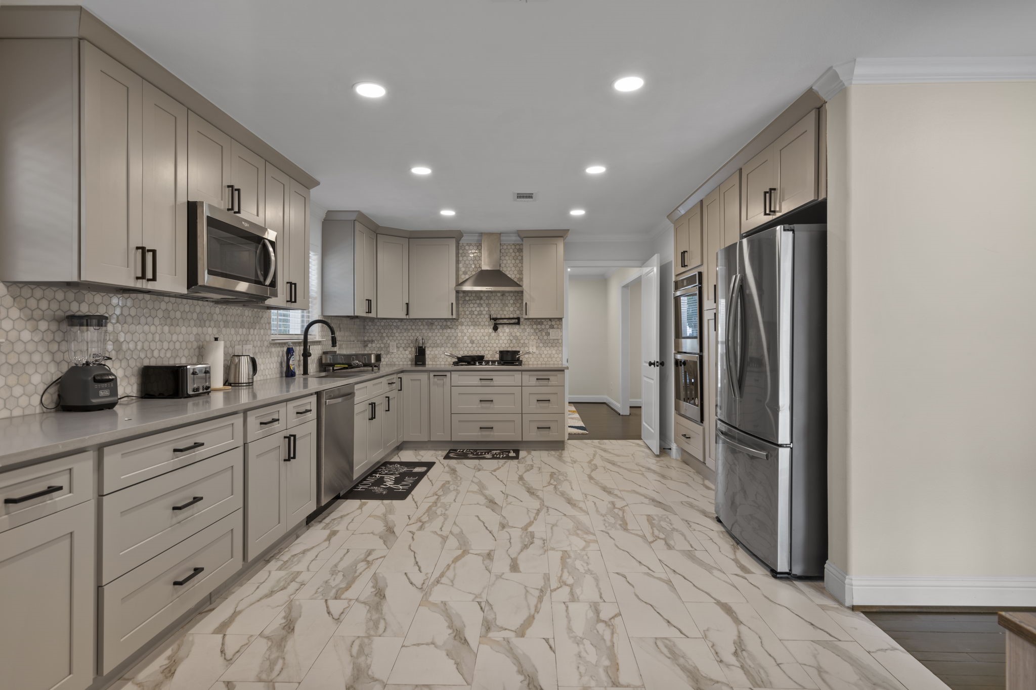 2402 Chimney Rock Road Houston, TX 77057 - Photo 7 of 36 Stunning kitchen featuring shaker cabinets, stainless steel appliances, and a designer tile backsplash.