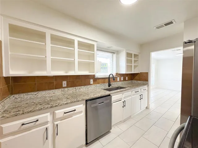 a kitchen with granite countertop stainless steel appliances white cabinets and a sink