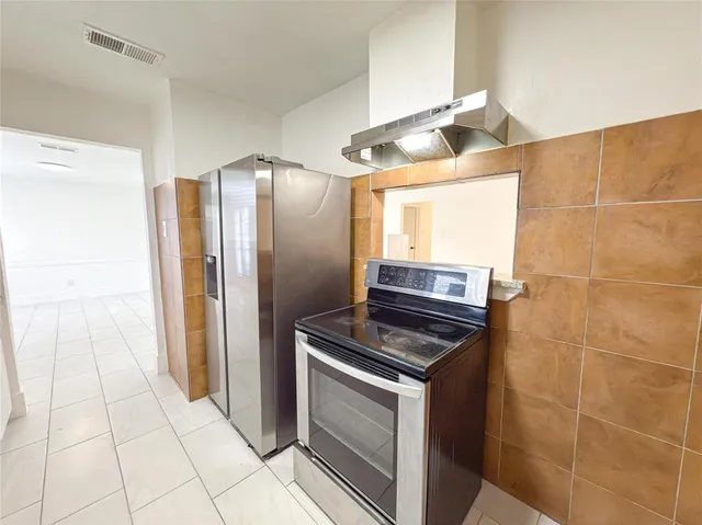 a kitchen with granite countertop a refrigerator and a stove top oven