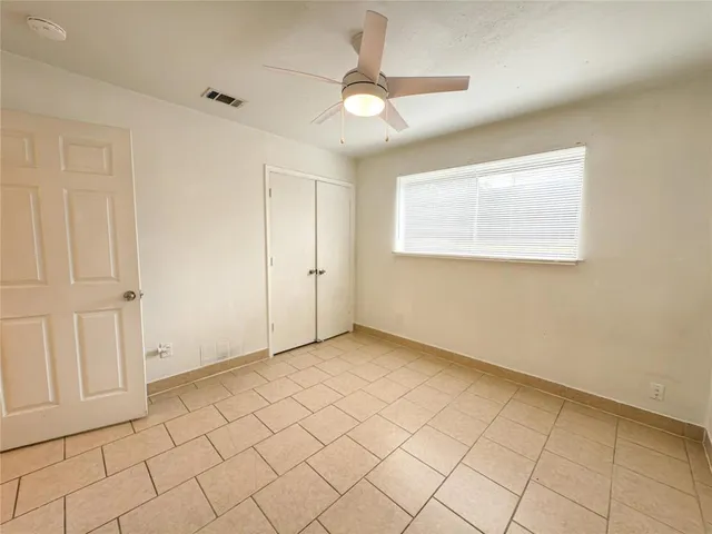 an empty room with windows and fan