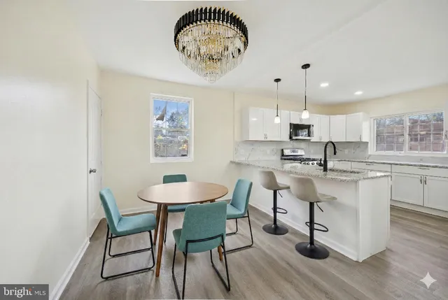a kitchen with stainless steel appliances a table and chairs in it