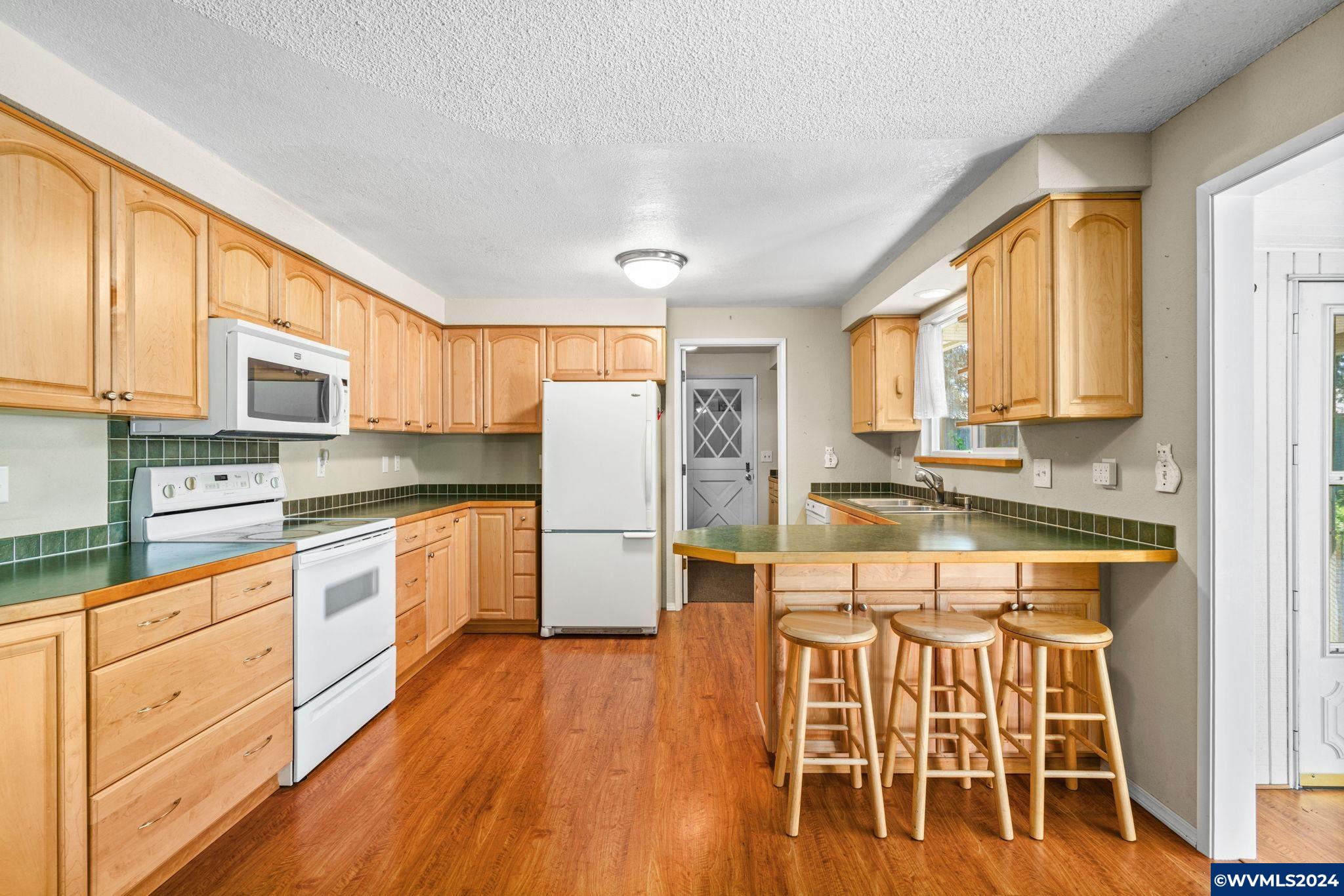 2254 8th Street Springfield, OR 97477 - Photo 7 of 34 a kitchen with stainless steel appliances granite countertop a refrigerator a stove a sink dishwasher and white cabinets with wooden floor