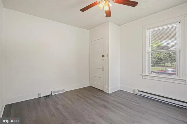 an empty room with a window and wooden floor