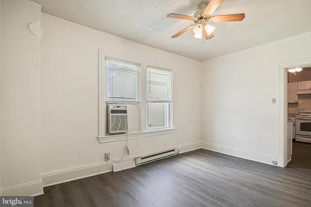 an empty room with wooden floor chandelier fan and windows