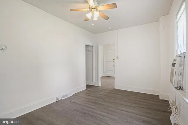 an empty room with wooden floor fan and windows