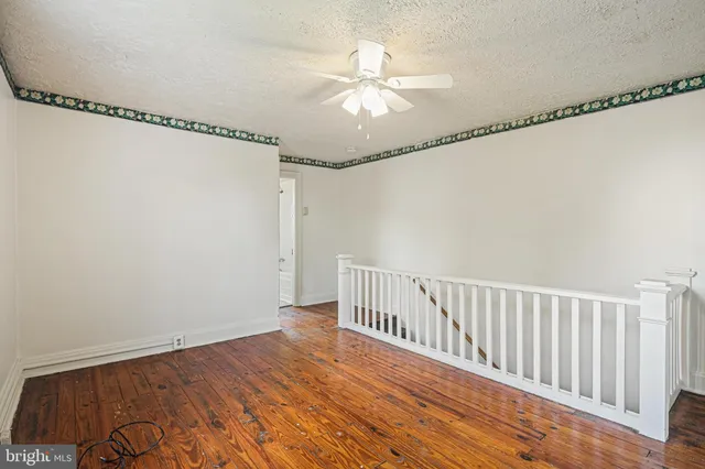 a view of a room with wooden floor fan and windows