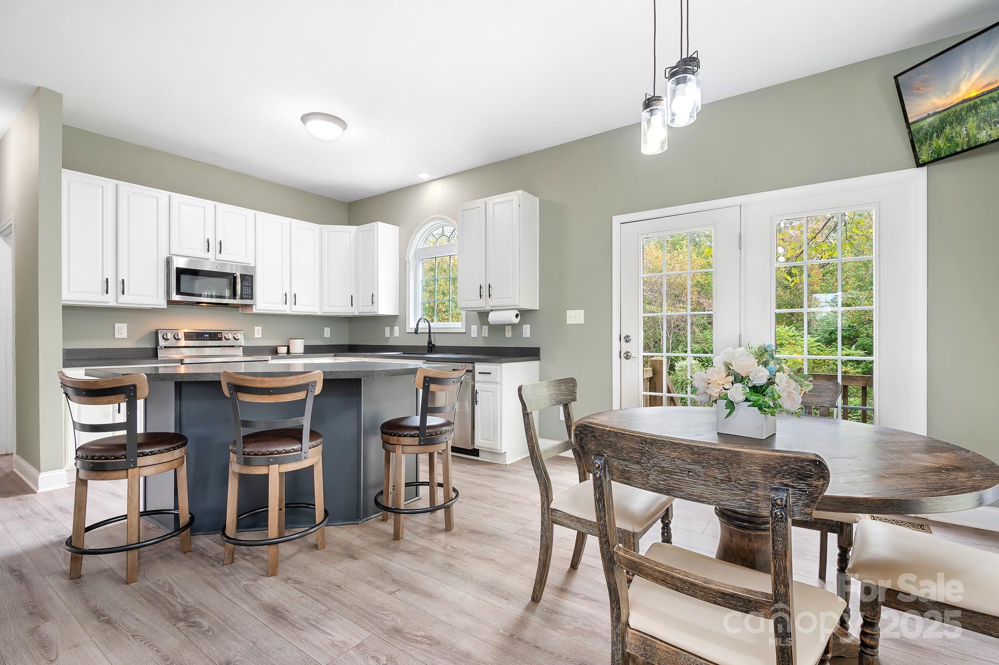 4654 Rocky Hollow Road Davidson, NC 28036 - Photo 12 of 48 a kitchen with kitchen island granite countertop a stove a sink a dining table and chairs with wooden floor