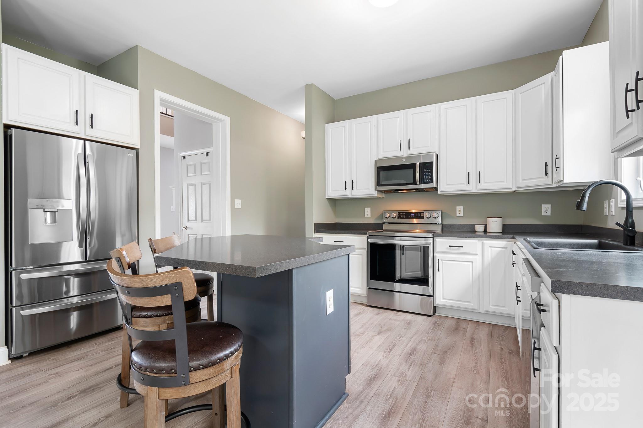 4654 Rocky Hollow Road Davidson, NC 28036 - Photo 13 of 48 a kitchen with granite countertop a stove top oven a sink dishwasher a dining table and chairs with wooden floor