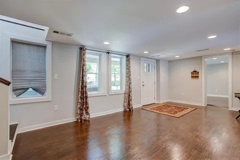 a view of an empty room with a window and wooden floor