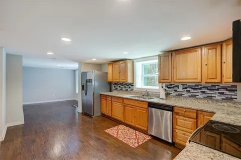 a kitchen with stainless steel appliances granite countertop a stove a sink dishwasher and a refrigerator with wooden floor
