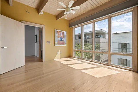a view of an empty room with a window and wooden floor