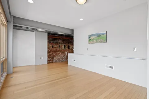 a view of an empty room with wooden floor and closet