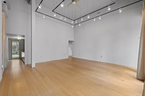 a view of a room with wooden floor and a ceiling fan