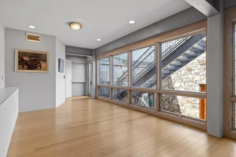 a view of an empty room with wooden floor and a window