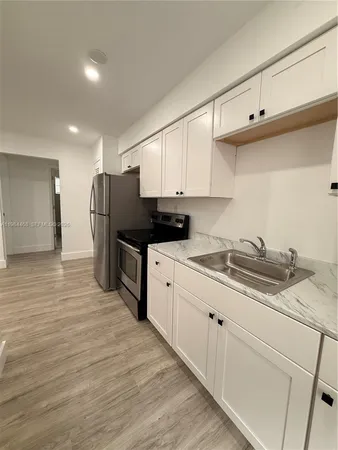 a kitchen with stainless steel appliances granite countertop a refrigerator sink and white cabinets
