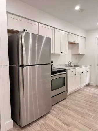 a kitchen with granite countertop a refrigerator sink and cabinets