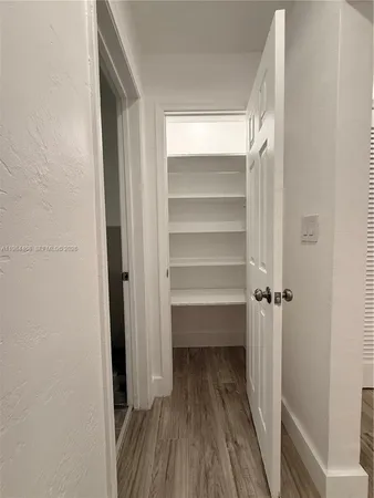 a view of a room with wooden floor and a door