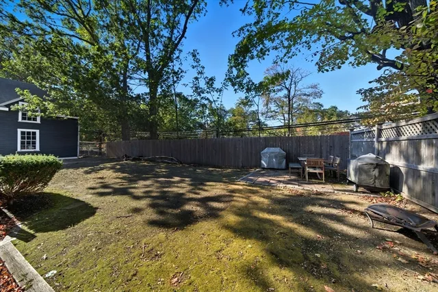 a backyard of a house with table and chairs and a large tree