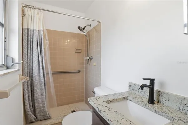 a bathroom with a granite countertop sink toilet and shower