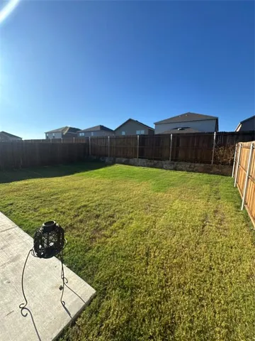 a view of a swimming pool with a yard and wooden fence