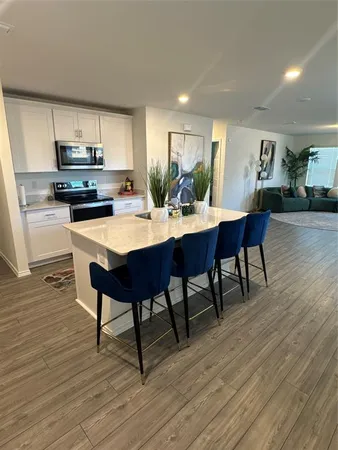 a kitchen with a dining table chairs and wooden floor