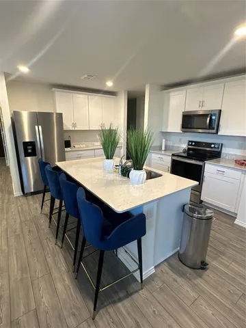 a kitchen with stainless steel appliances a dining table chairs stove refrigerator and microwave