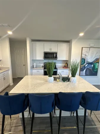 a kitchen with stainless steel appliances granite countertop a table chairs and a refrigerator