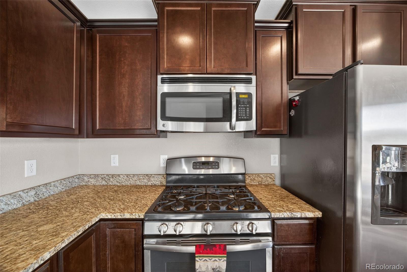 10247 Olathe Way Commerce City, CO 80022 - Photo 11 of 37 a kitchen with granite countertop stainless steel appliances and wooden cabinets