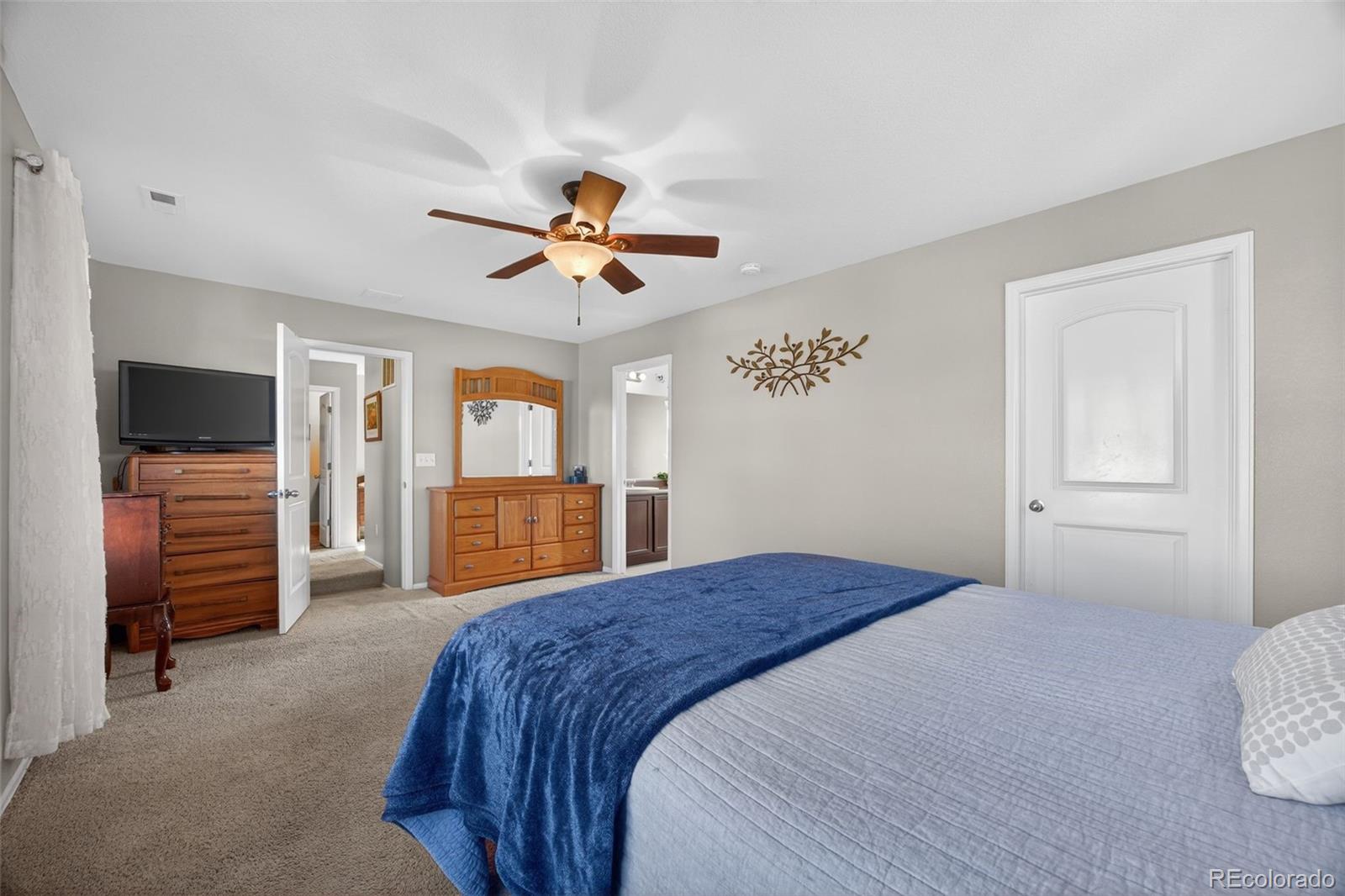10247 Olathe Way Commerce City, CO 80022 - Photo 25 of 37 a bedroom with a large bed a flat tv screen and dresser