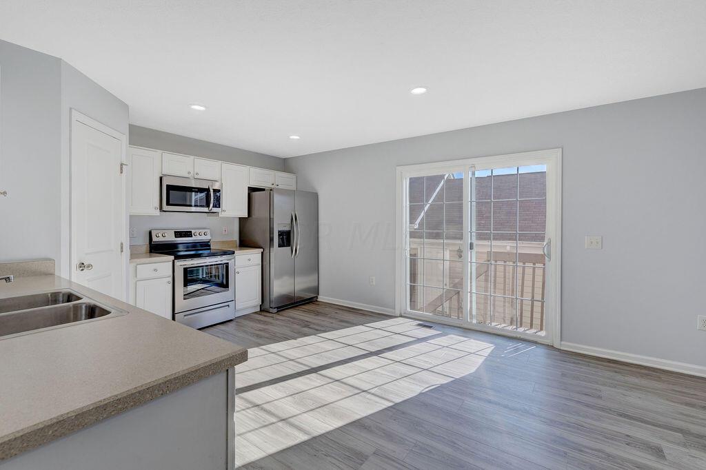 6345 Needletail Road, Unit 24634 Columbus, OH 43230 - Photo 7 of 58 • New luxury vinyl plank flooring ~ 2021 • Gray painted walls • Bevelled edge countertops • White, raised panel cabinets • Double bowl, stainless steel sink • New Frigidaire® dishwasher ~ 2021 • New Frigidaire® electric range ~ 2021 • New Frigidaire® microwave ~ 2021 • New Frigidaire® refrigerator ~ 2021 • Step-in pantry closet • Can lighting • Insinkerator® disposal • New double sliding doors (2020) to privacy fenced, paver patio