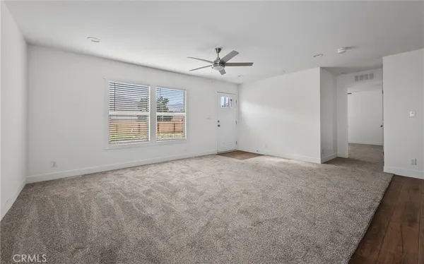 an empty room with windows and ceiling fan