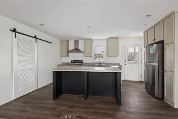a kitchen with kitchen island granite countertop a refrigerator and a sink