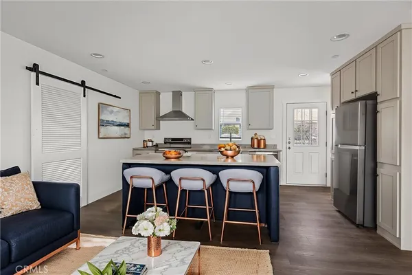 a living room with stainless steel appliances granite countertop a couch and wooden floor